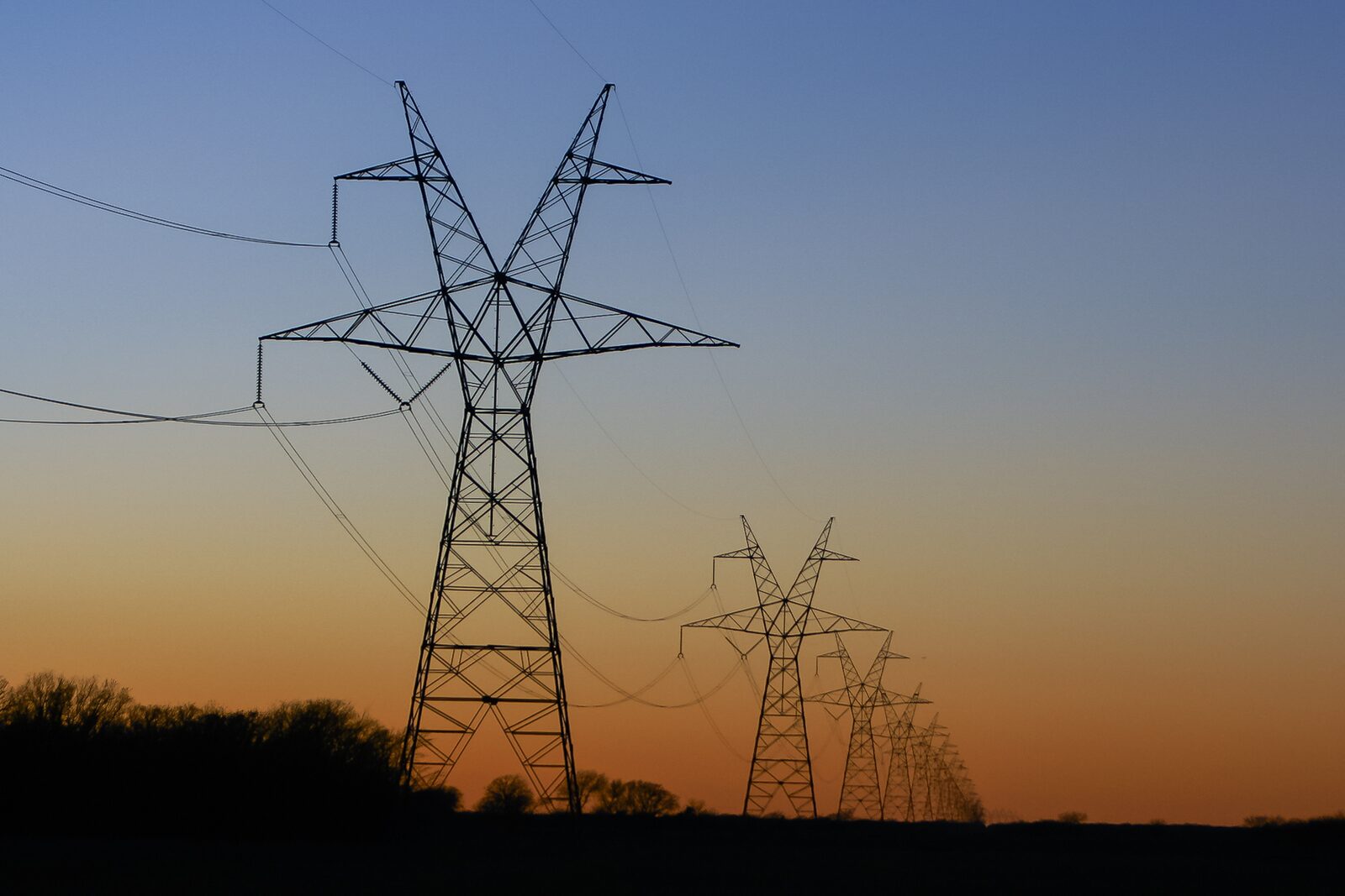High-voltage transmission towers at sunset — representative utility asset for power-line drone inspection programs